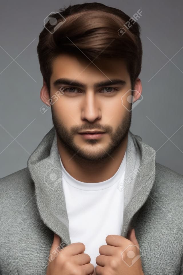 Portret van een jong mannelijk model met mooi gezicht en handen op zijn jas