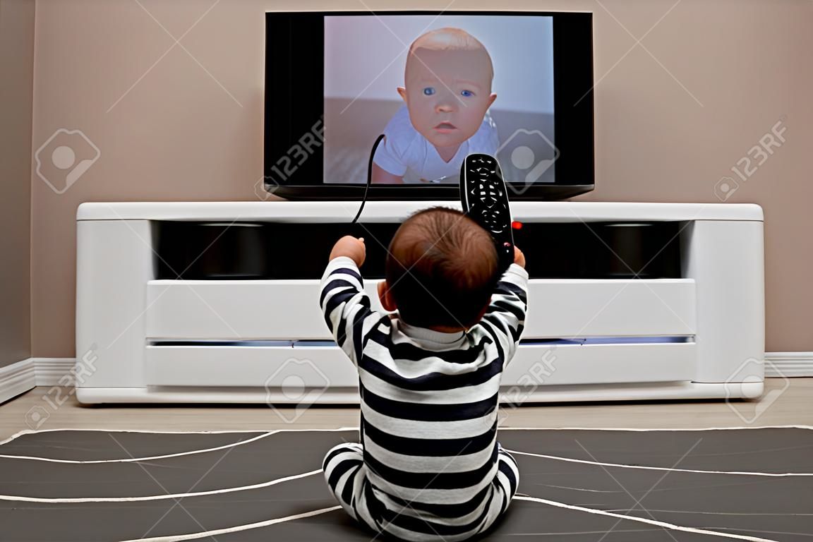 Bebé con los mandos a distancia viendo la televisión