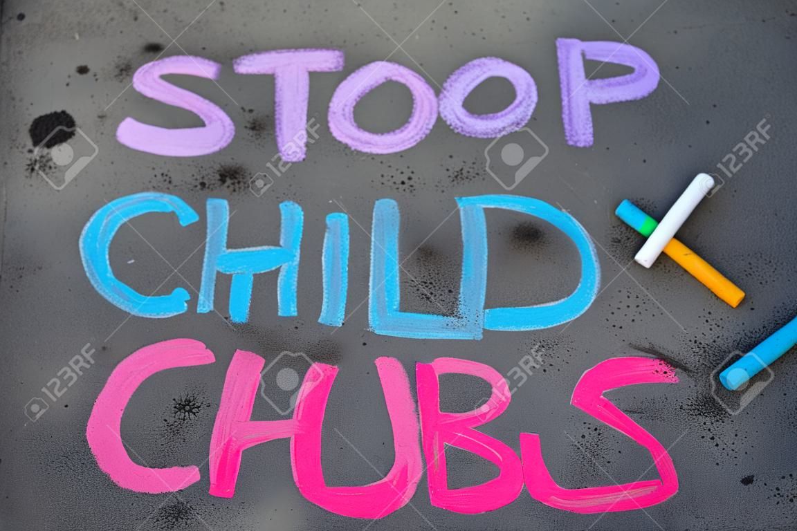 Colorful chalk drawing on asphalt: words STOP CHILD ABUSE