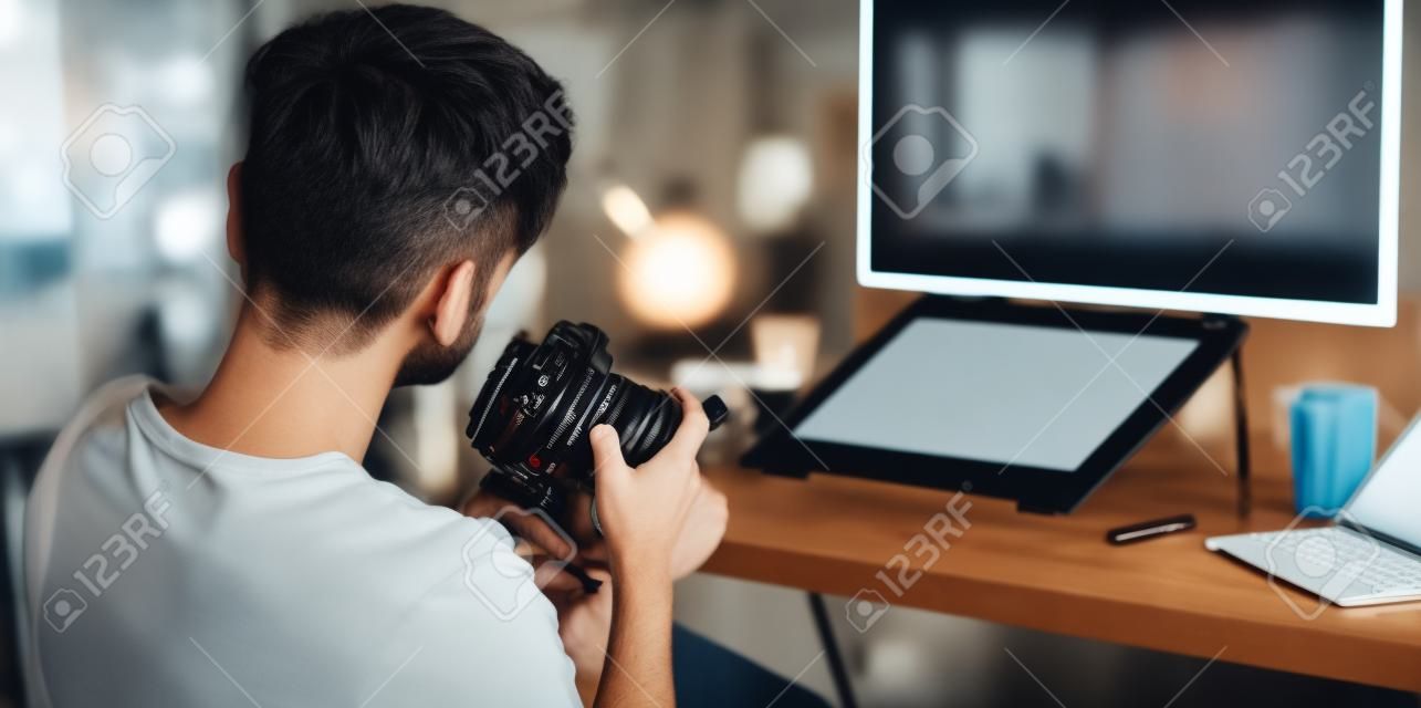 Close-up view of motivated photographer checking his camera in his modern workplace