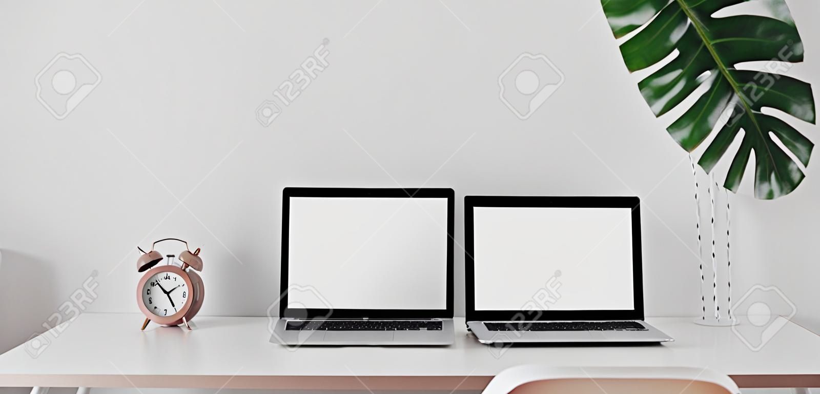 Modern workspace with open blank screen laptop computer and mock up frame with decorations on white wooden table