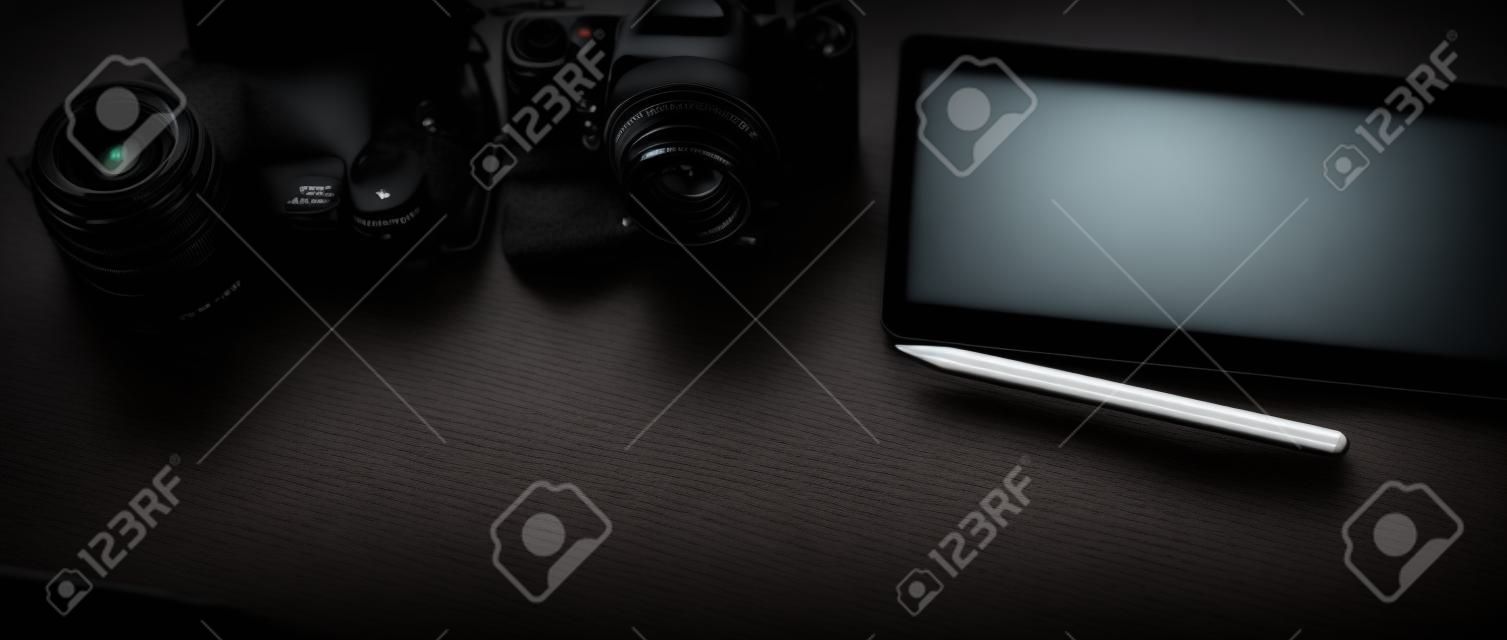 Cropped shot of dark modern photographer workspace with mock-up tablet, camera, decoration and copy space