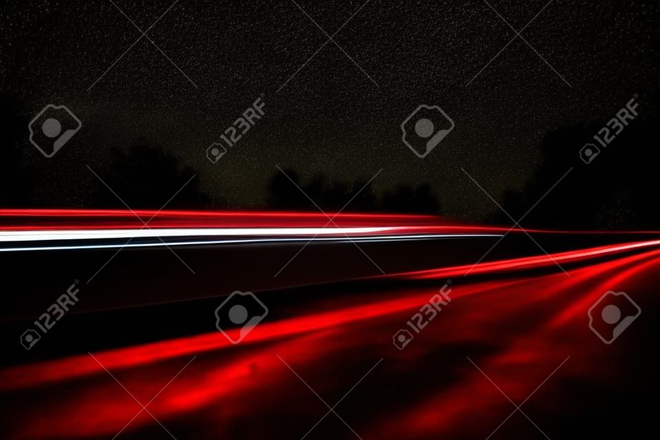 Beautiful, abstract car lights on a country road. TRaffic in the night, looking from a roadside. Long exposure photo.