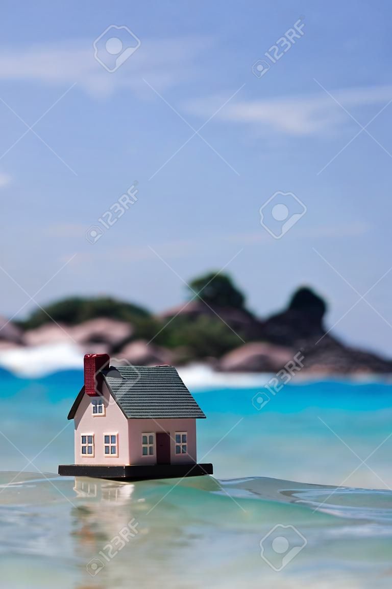 Une maison de jouets sur fond de vagues. plage de sable