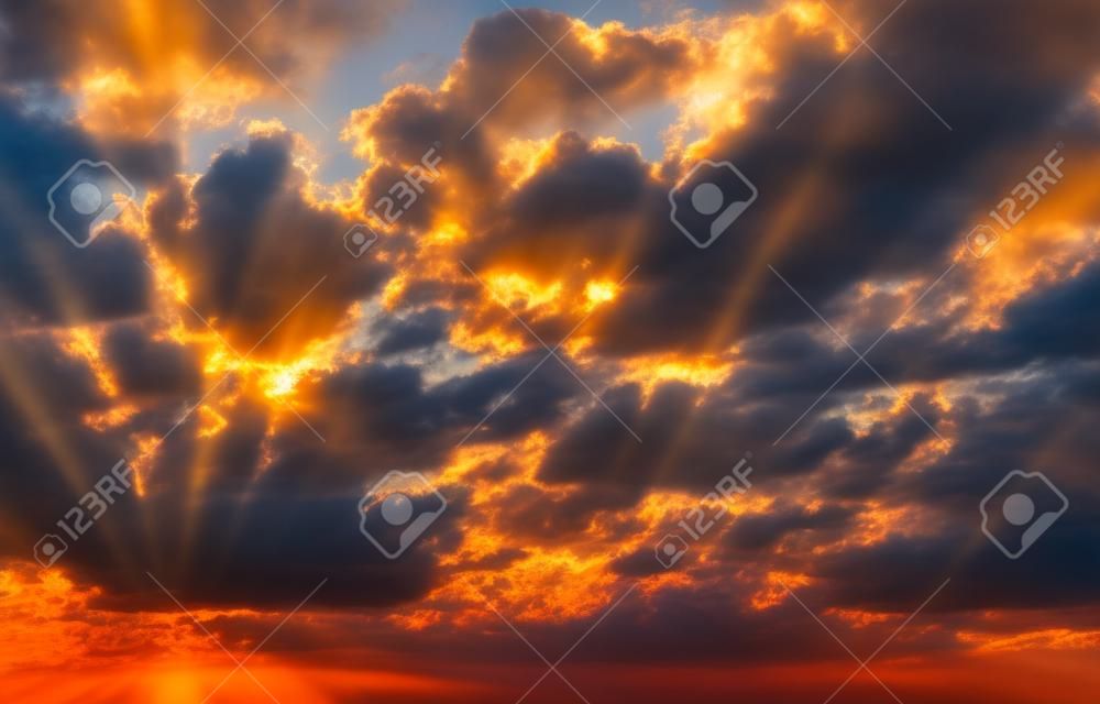 Die hellen Sonnenstrahlen in den dramatischen Wolken im Morgengrauen. Abstrakte Sonnenuntergangskomposition