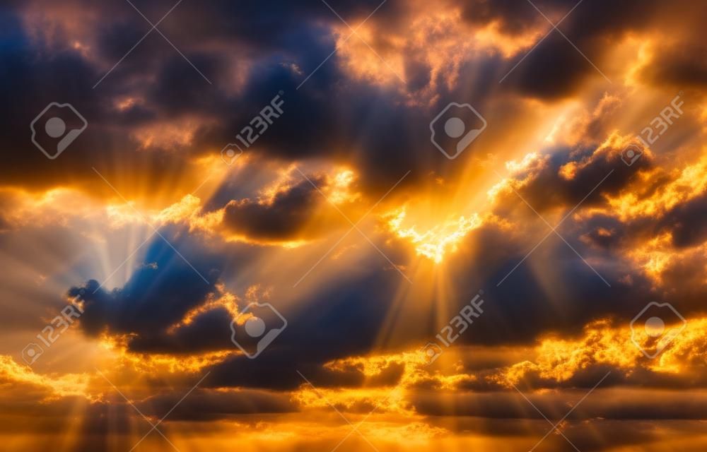 I raggi luminosi del sole nelle nuvole drammatiche all'alba. Composizione astratta al tramonto