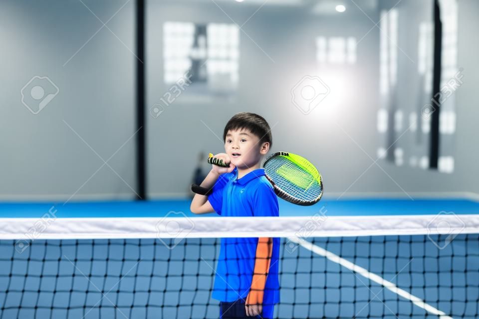 Monitoruj nauczanie dziecka klasy Padel, jego uczeń - trener uczy małego chłopca, jak grać w Padla na krytym korcie tenisowym