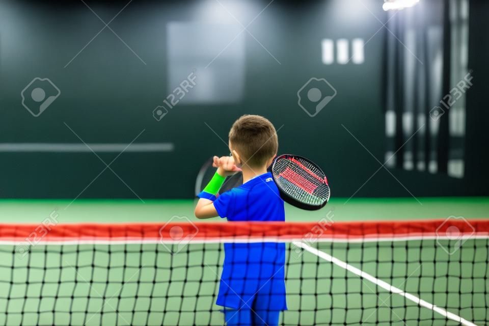 Monitora l'insegnamento della lezione di padel a un bambino, il suo studente - L'allenatore insegna al bambino come giocare a padel su un campo da tennis indoor