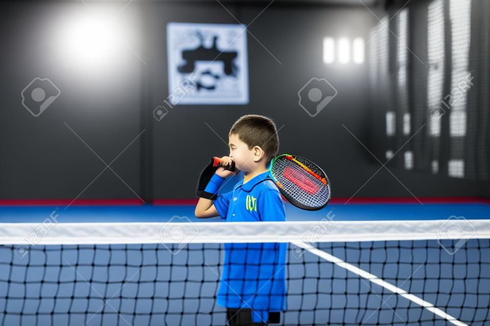 Monitora l'insegnamento della lezione di padel a un bambino, il suo studente - L'allenatore insegna al bambino come giocare a padel su un campo da tennis indoor