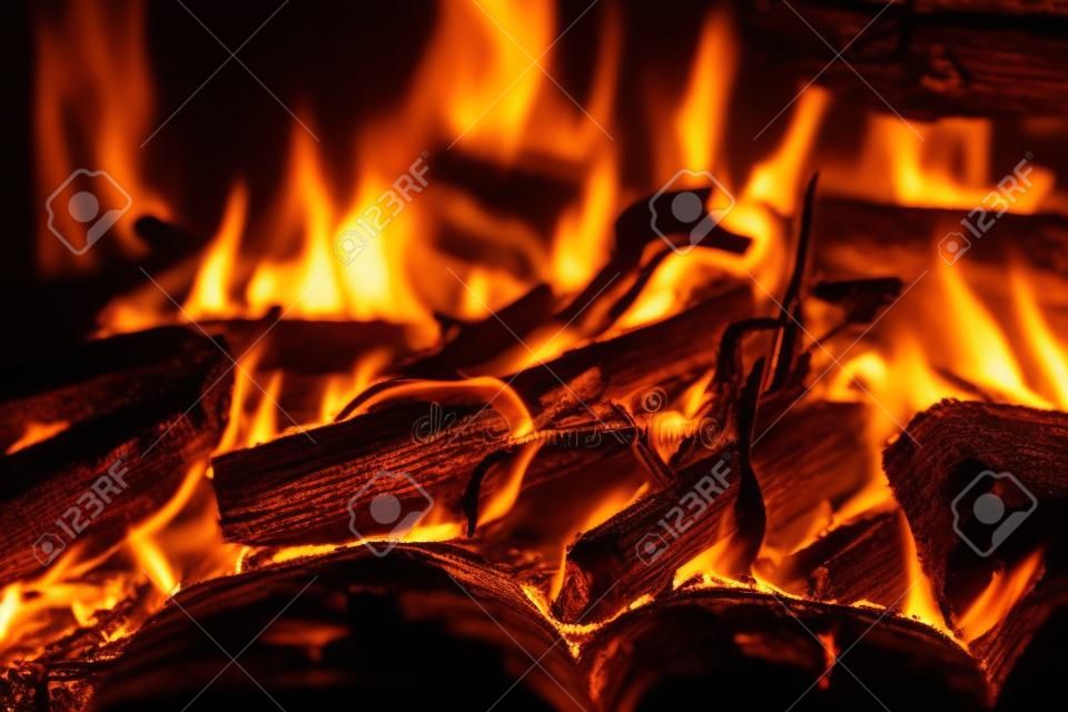 생생한 그을린 장작이 불에 가까이서 타올랐다. 모닥불의 주황색 불꽃이 있는 따뜻한 분위기의 배경. 모닥불의 상상할 수 없는 풀 프레임 이미지. 아름다운 불에 불타는 통나무. 멋진 불꽃.