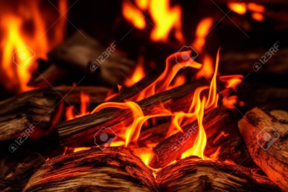 생생한 그을린 장작이 불에 가까이서 타올랐다. 모닥불의 주황색 불꽃이 있는 따뜻한 분위기의 배경. 모닥불의 상상할 수 없는 풀 프레임 이미지. 아름다운 불에 불타는 통나무. 멋진 불꽃.