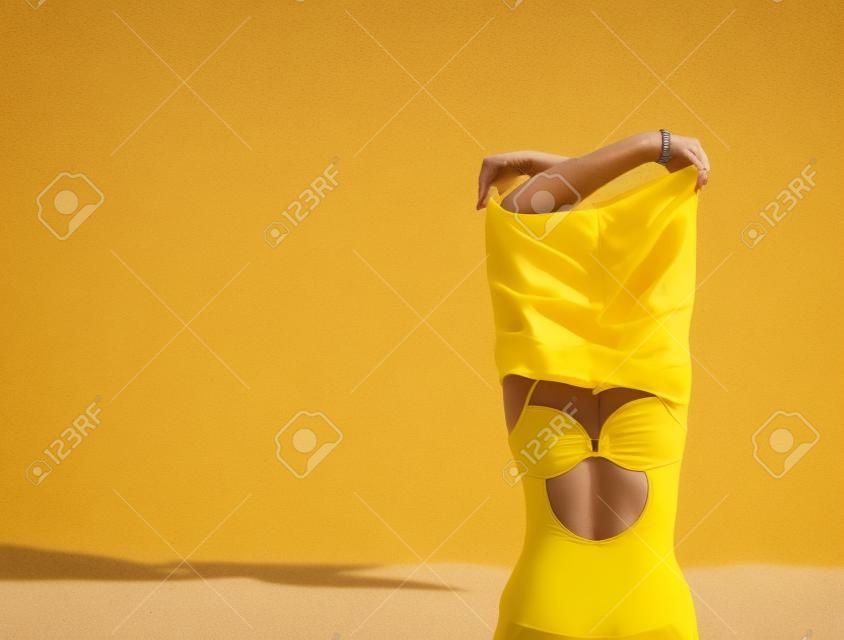 Primo piano di un sedere femminile in costume da bagno giallo. Una giornata in un concetto di spiaggia.