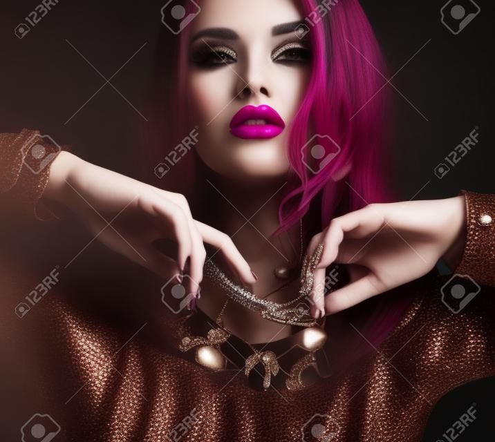 Studio moda ritratto di donna bellissima con i capelli scuri e trucco luminoso con lussuosi bijou, collana e bracciali massicci