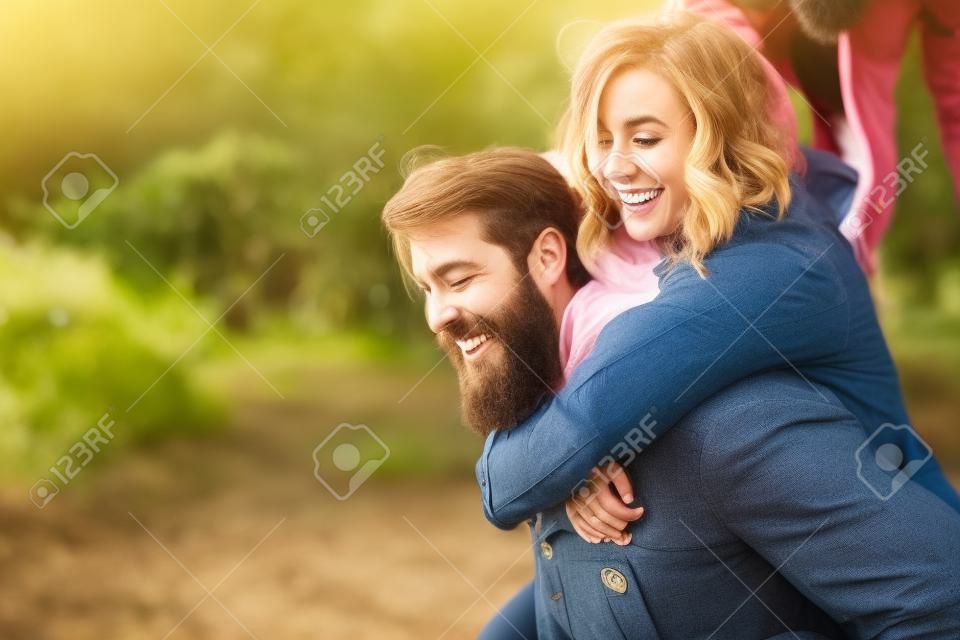Una pareja indie genial que se divierte al aire libre mientras él la lleva a cuestas.