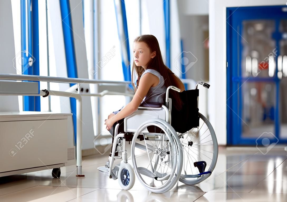 Uma jovem em uma cadeira de rodas está de pé no corredor do hospital