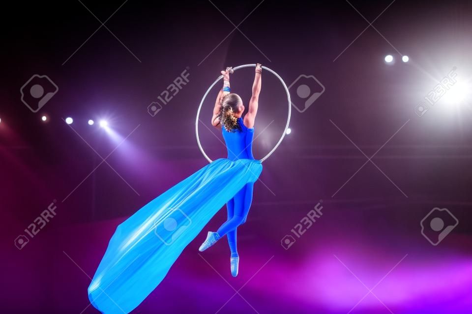 Aerial acrobat in the ring. A young girl performs the acrobatic elements in the air ring
