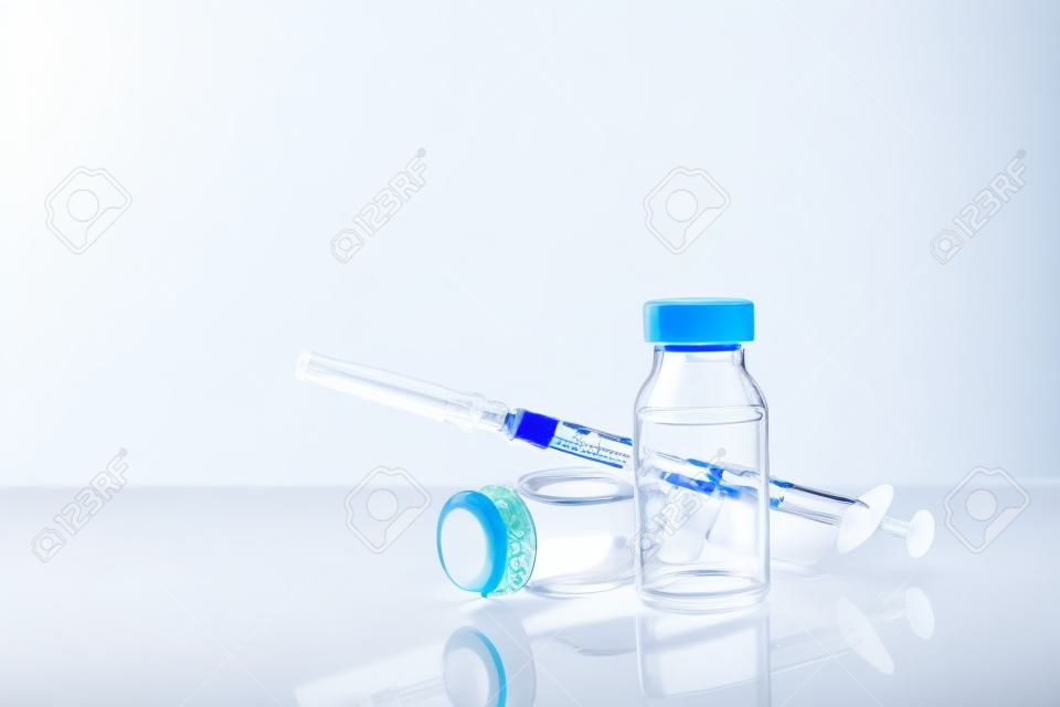 Vials with medication and syringe on white methacrylate table with window background. Horizontal composition. Front view.