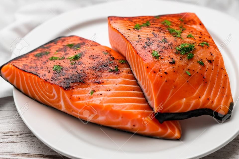 Fresh salmon fillets with skin on a white plate
