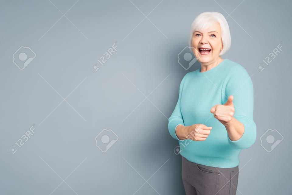 2つの人差し指を指す自信に満ちた現代のおばあちゃんの肖像画