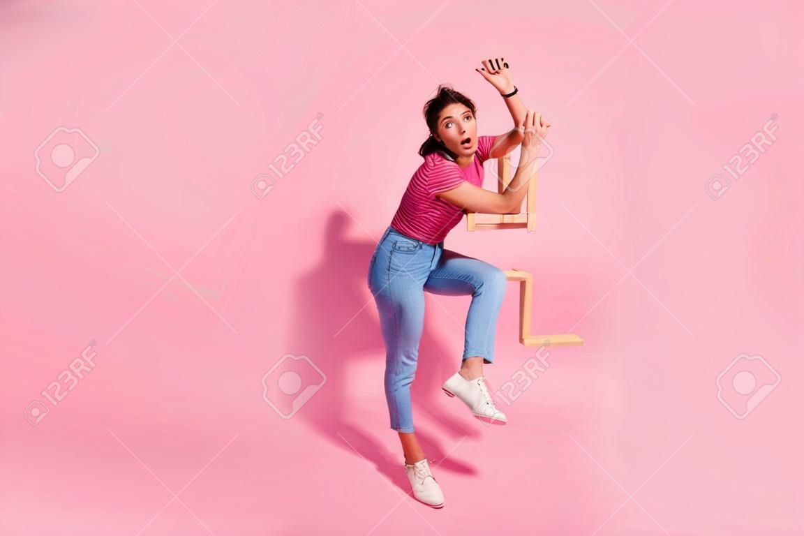 분홍색 배경에 고립된 삶의 경계선을 벗어나려고 하는 캐주얼한 줄무늬 티셔츠 청바지를 입은 그녀의 전체 길이 신체 크기 보기