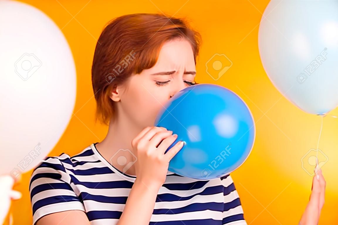 Close-up portrait of nice charming attractive girlish childish lady blowing blue baloon festal event celebratory day preparation tradition isolated over bright vivid shine yellow background