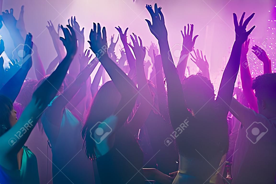 Close up photo of many birthday party people dancing clubbing purple lights confetti fog nightclub hands raised shiny formal-wear