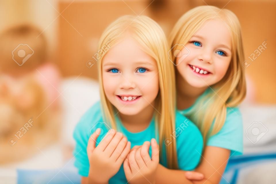 Close up photo of charming children blonde brunette hair have bonding feel satisfied sit bed indoors room have sleepover