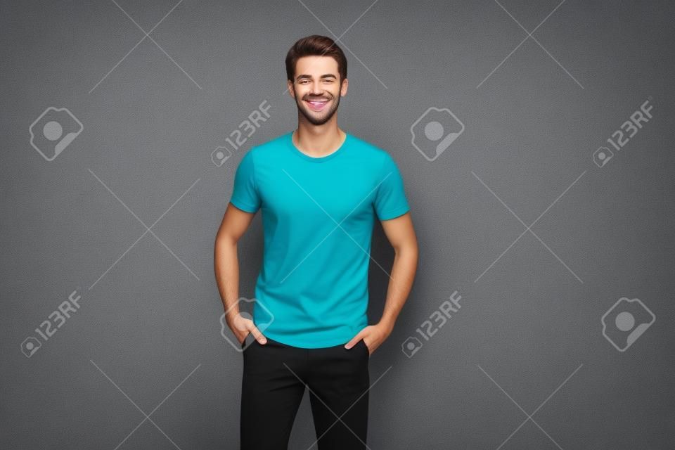 Foto di un uomo allegro e attraente che si tiene per mano nelle tasche dei suoi pantaloni neri che sorride a trentadue denti con le setole isolate su uno sfondo di colore vibrante