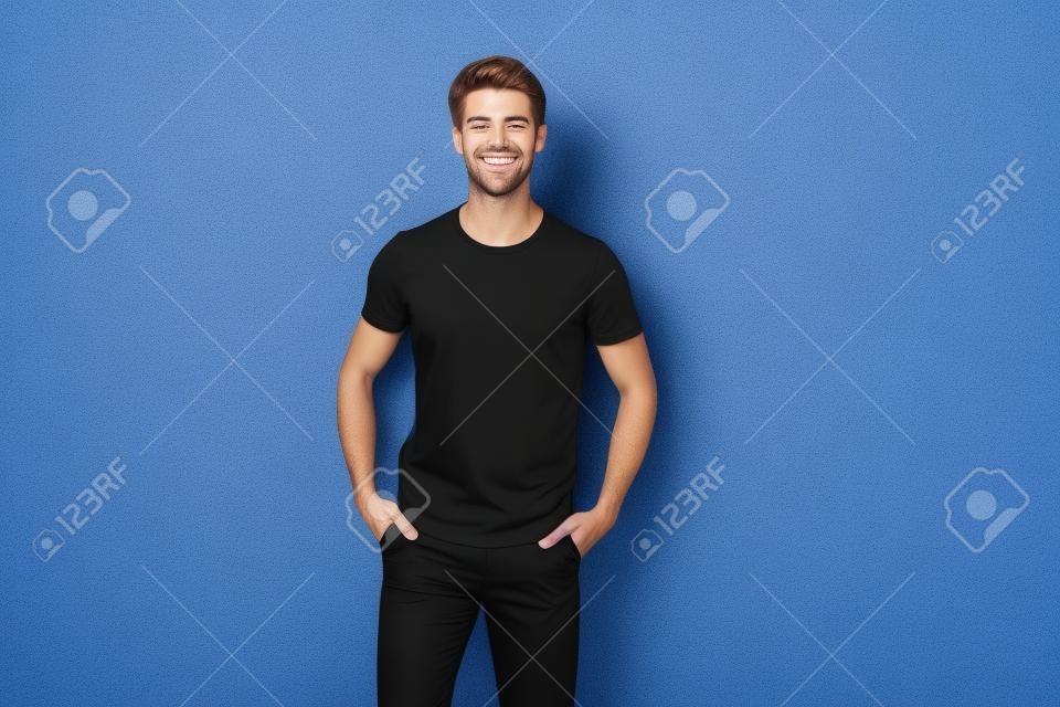 Foto di un uomo allegro e attraente che si tiene per mano nelle tasche dei suoi pantaloni neri che sorride a trentadue denti con le setole isolate su uno sfondo di colore vibrante