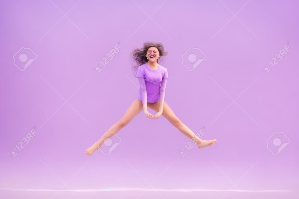 라일락 보라색 보라색 파스텔 색상 배경에서 고립되어 즐겁게 뛰어다니는 그녀의 전체 길이 신체 크기 보기