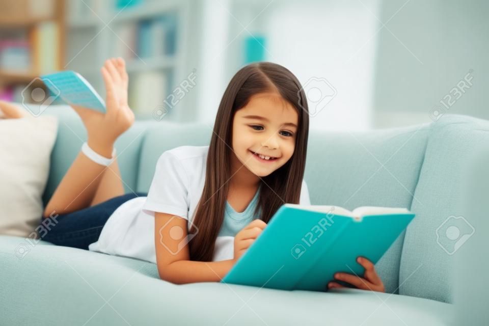 Photo of little pretty pupil school lady lying comfy sofa reading diary book positive good mood diligent student write notes pencil social distance quarantine home study comfort room indoors
