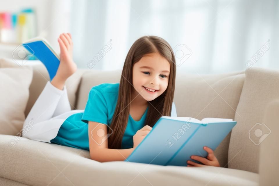 Photo of little pretty pupil school lady lying comfy sofa reading diary book positive good mood diligent student write notes pencil social distance quarantine home study comfort room indoors