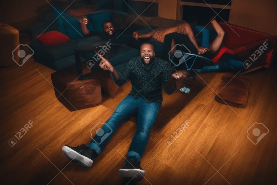 Je ne me souviens pas de la soirée. Haut au-dessus de la vue en grand angle photo complète du corps d'un homme afro-américain assis au sol tenir une bouteille de bière vide hausser les épaules ont passer ses copains dormir dans la maison à l'intérieur