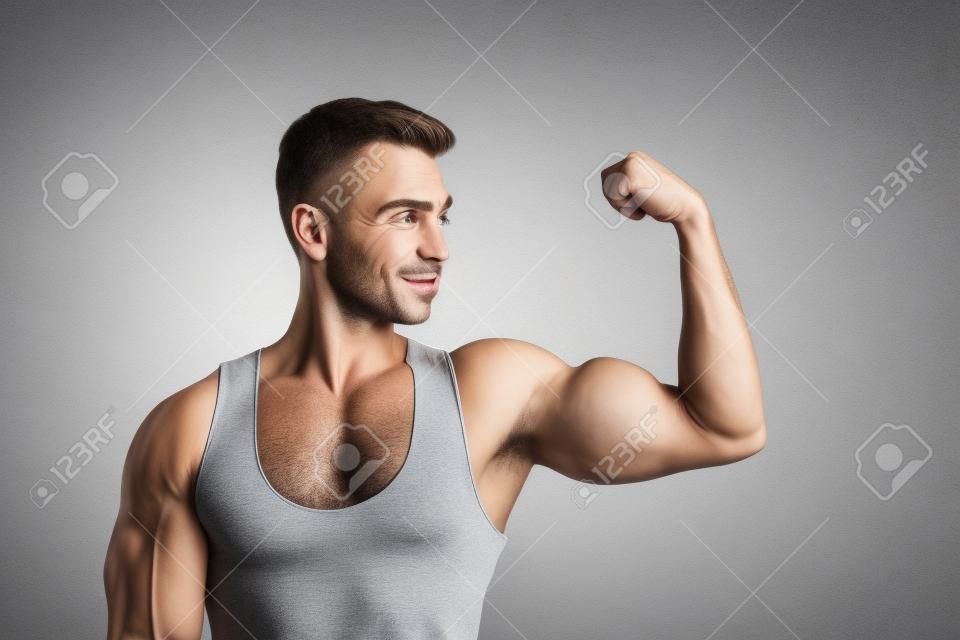 Close-up portrait of his he nice attractive sportive successful muscular cheery guy demonstrating looking at powerful muscles goal protein diet isolated over light gray pastel color background