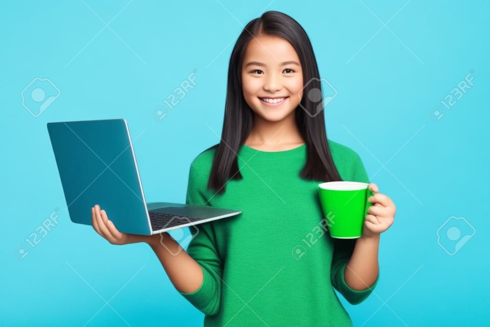 Foto van positieve meisje houden laptop cacao beker dragen groene pullover geïsoleerd over blauwe kleur achtergrond