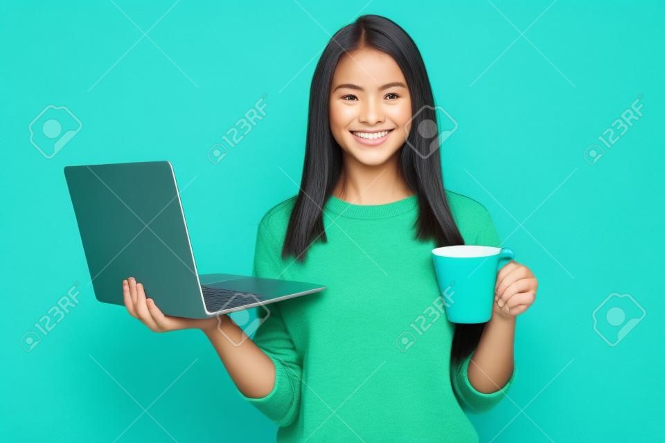 Foto van positieve meisje houden laptop cacao beker dragen groene pullover geïsoleerd over blauwe kleur achtergrond