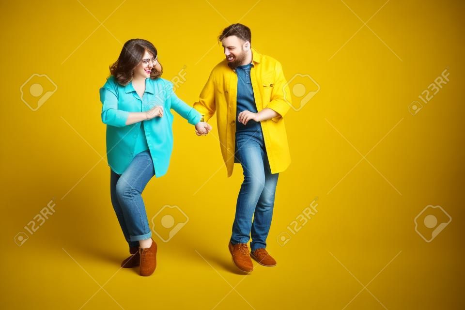 Photo de douce adorable mari femme porter des chemises jeans dansant espace vide fond de couleur jaune isolé