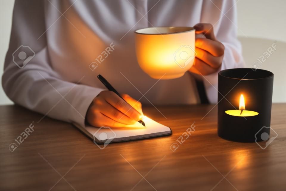 여성의 손을 펜 및 차 또는 커피 촛불에 촛불에 쓰기