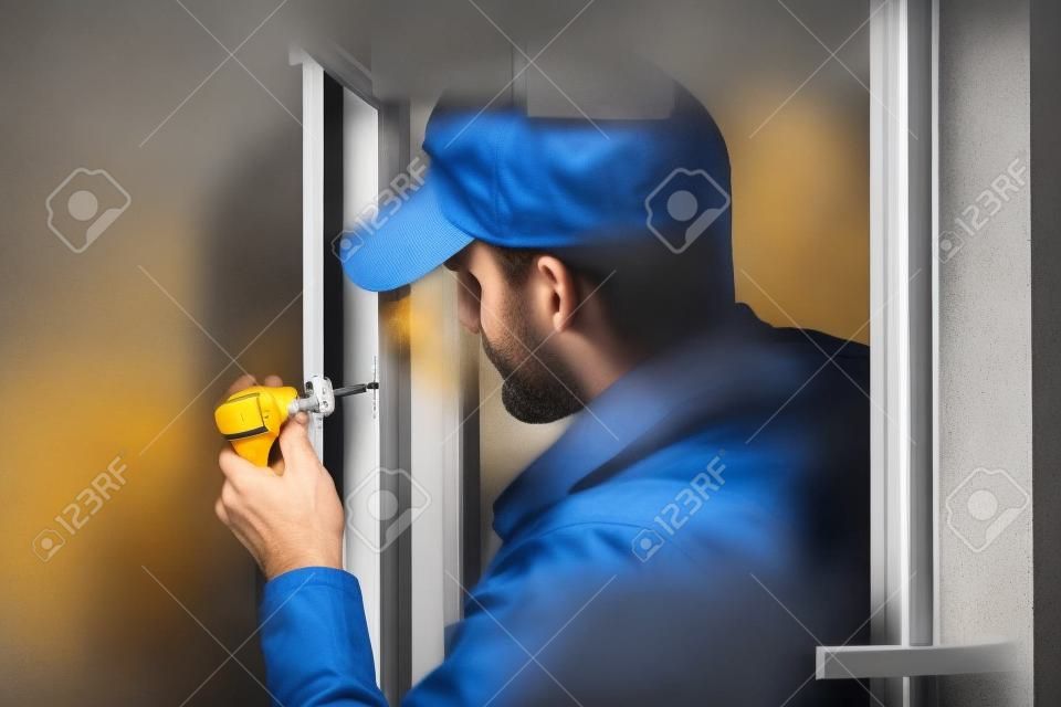 człowiek usługi instalacji okna z śrubokrętem