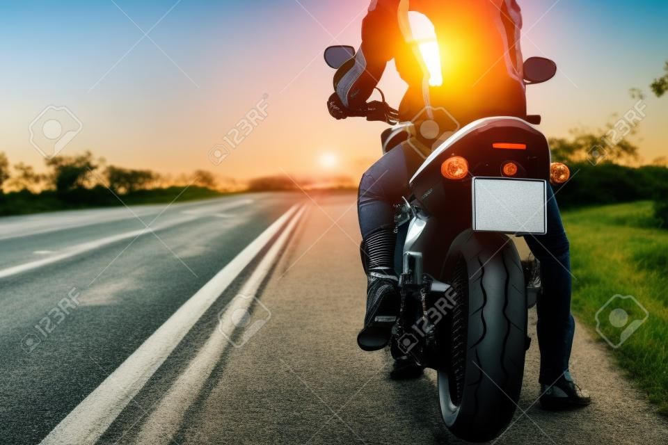 Vista posteriore della moto sul lato della strada mentre la bici è in viaggio per viaggiare in bicicletta contro l'alba.