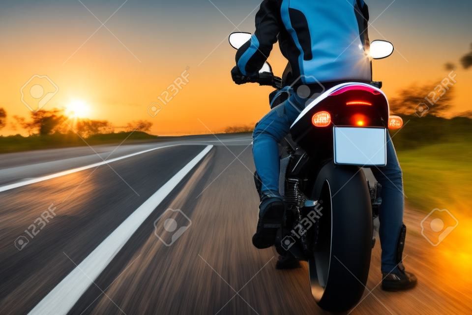Vista posteriore della moto sul lato della strada mentre la bici è in viaggio per viaggiare in bicicletta contro l'alba.