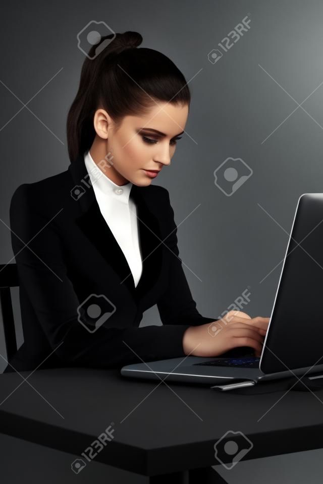 Spy girl in a black suit with laptop