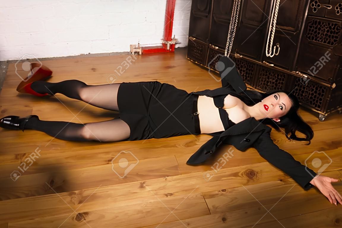 Detective scène imitatie. Vrouw in een zwart pak met pistool liggen op de vloer
