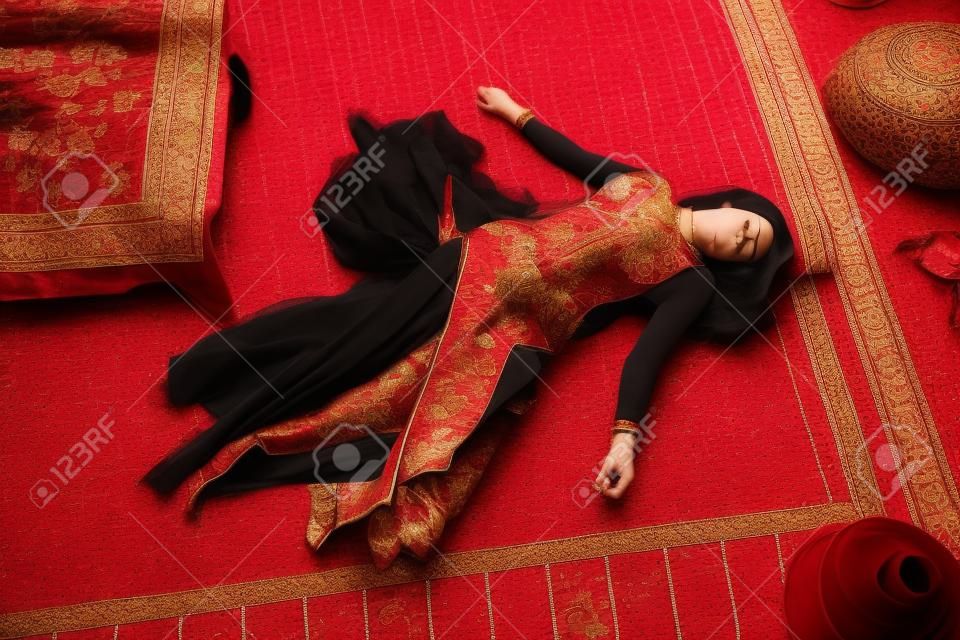 Imitazione della scena del crimine: donna senza vita in un tradizionale costume orientale sdraiata su un pavimento