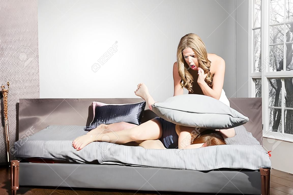 致命的な喧嘩。一人の女性が枕で別の女性の首を絞める。