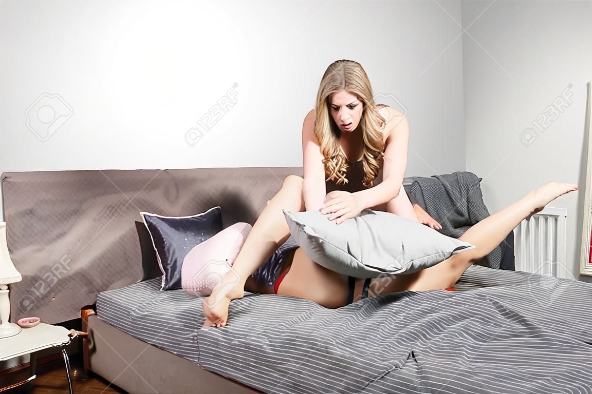 致命的な喧嘩。一人の女性が枕で別の女性の首を絞める。