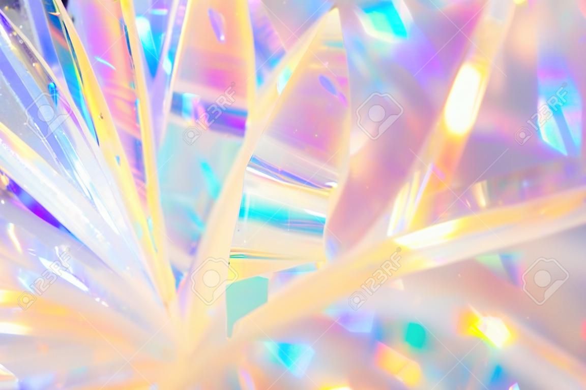 Abstrakcyjny, promienisty świąteczny wesołe wakacje tło tekstury obraz holograficznej opalizującej metalowej wstążki dekoracji z ciepłą, jasną poświatą i błyszczącymi kryształowymi refleksami lodu i światłem bokeh