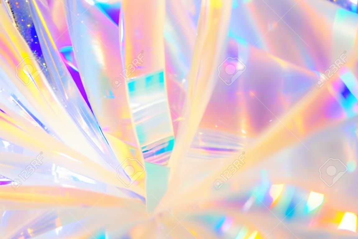 Abstract radiant festive merry holiday backdrop texture image of holographic iridescent metallic foil ribbon decoration with warm bright glow and sparkling crystal ice reflections and bokeh light