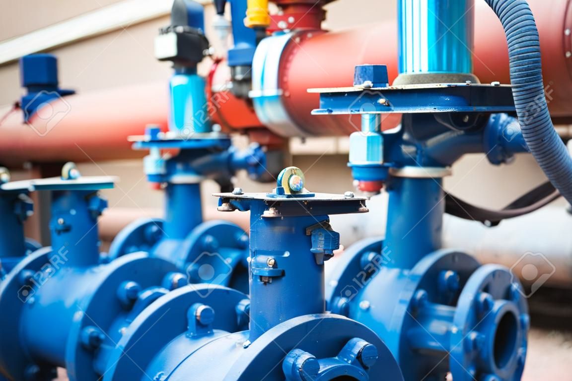 Gate valves installed on pipes painted in blue. Industrial background.