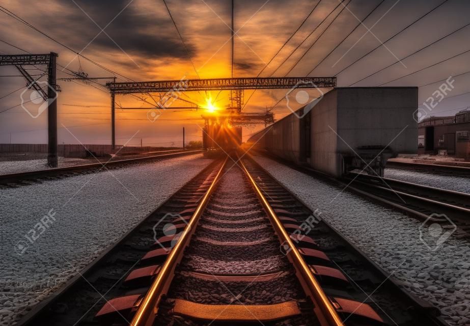 Plataforma de trem de carga ao pôr do sol. Ferrovia na Ucrânia. Estação ferroviária.